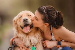A woman kissing a golden retriever